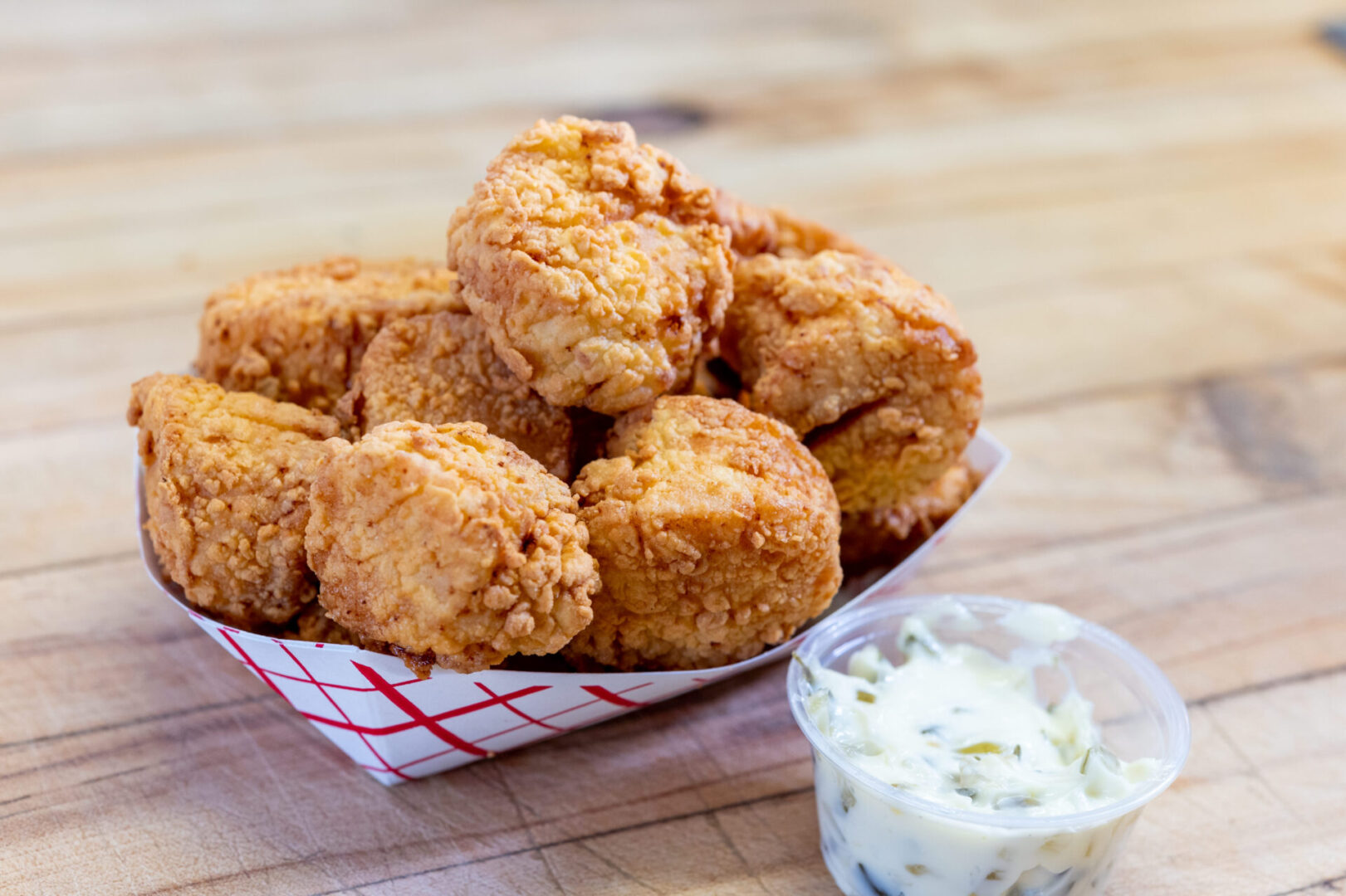 A basket of fried food with dip in the background.